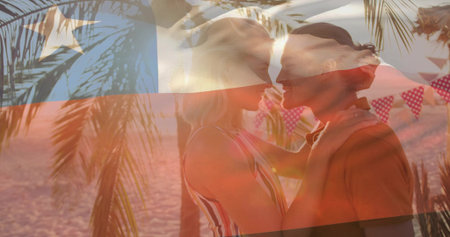 Leaning romantic couple sharing sunset kiss on sandy beach, with fronds, pennants and flag overlay....