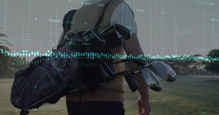 Walking Chinese golfer carrying golf bag with clubs across dawn golf fairway, floating chart line. Athletic, leisure, sport, outdoor, elegance, activity, traditionalの写真素材