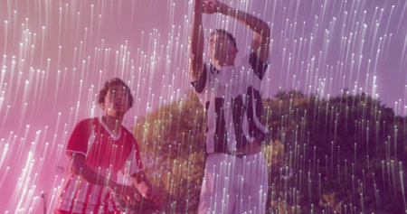 Men wearing striped jerseys and shorts raising arms and watching on field, with light streaks. Sports, athleticism, outdoor, energetic, vibrant, teamwork, fitnessの写真素材