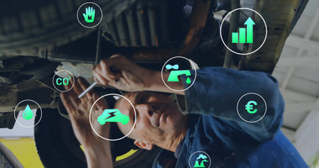Working mechanic using wrench under vehicle lift in brightly lit garage with digital icons. Automotive, industrial, maintenance, repair, technology, efficiency, sustainabilityの写真素材