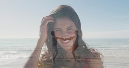 Featuring smiling white woman in red top touching hair on shoreline, with dancing couple in surf. Joy, connection, leisure, outdoor, lifestyle, harmony, vibrantの写真素材
