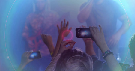 Recording fan raising smartphone under colored spotlights in packed venue, capturing performers. Audience, energy, nightlife, entertainment, vibrant, immersive, clubの写真素材