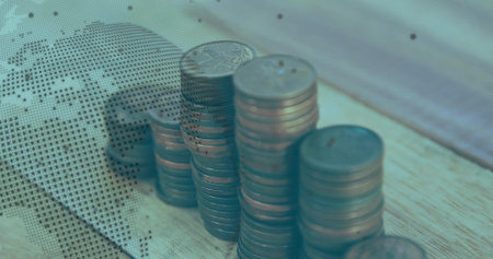 Rising copper coin stacks occupying wooden office desk, featuring dotted world map overlay....