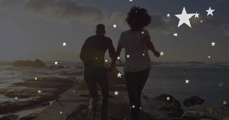 Walking man and woman holding hands along narrow stone pier into ocean sunset. Romance, adventure,...