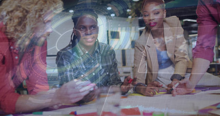 Collaborating group wearing casual attire designing at office table, with markers and AR overlay. Collaboration, innovation, teamwork, creativity, digital, workspace, brainstormingの写真素材
