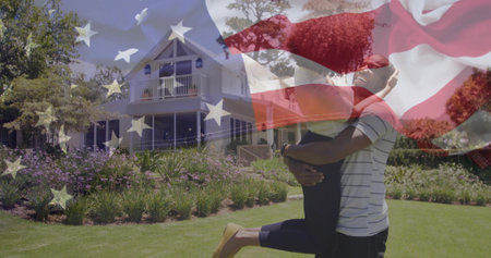 Lifting man holding woman on residential lawn, with house balcony and flag overlay, copy space. Romantic, affection, outdoor, idyllic, vibrant, companionship, architectureの写真素材