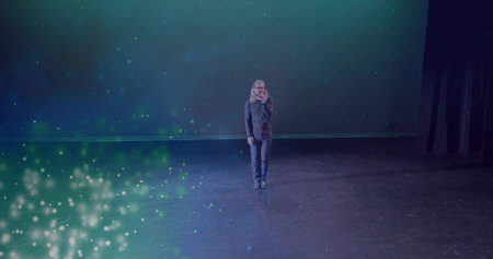 Performing male performer singing in dark clothing on theater stage, with handheld microphone. Performer, spotlight, minimalism, stagecraft, monologue, dramatic, entertainmentの写真素材