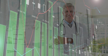 Standing senior male doctor crossing arms at clinic with stethoscope, financial data, copy space. Medical, finance, healthcare, analytics, professional, corporate, technologyの写真素材