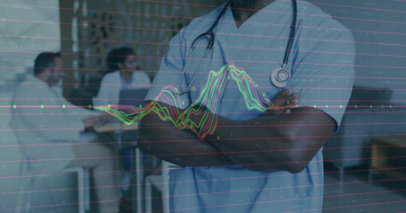 Standing doctor in blue scrubs crossing arms in lounge, with stethoscope, digital graph overlay. Medical team, collaboration, healthcare, digital technology, professional, clinical, innovationの写真素材