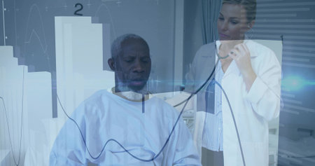Examining doctor using stethoscope on male patient wearing gown in exam room, with digital graphs....