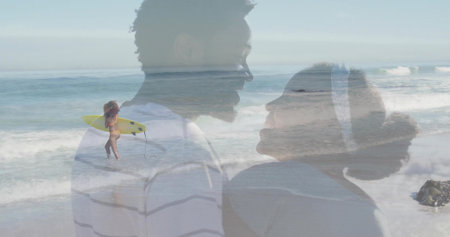 Smiling couple standing at seaside beach, with yellow surfboard, rolling waves and rocky outcrop. Peoples, romance, leisure, outdoor, lifestyle, vibrant, adventureの写真素材