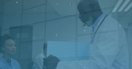 Holding blue folder, doctor with stethoscope presenting it to colleagues in clinic, copy space. Medical team, healthcare professionals, hospital, clinical environment, professionalism, collaboration, examination roomの写真素材