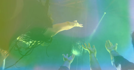 Reaching partygoers raising arms toward disco ball in nightclub, with spotlights and bracelets. Celebration, nightlife, energy, movement, vibrant, entertainment, raveの写真素材