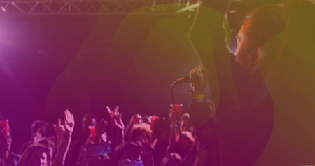 Holding microphone male singer raising hand in music venue, with smartphones, truss, copy space. Concert, live performance, entertainment, stage lighting, music industry, crowd energy, nightlifeの写真素材