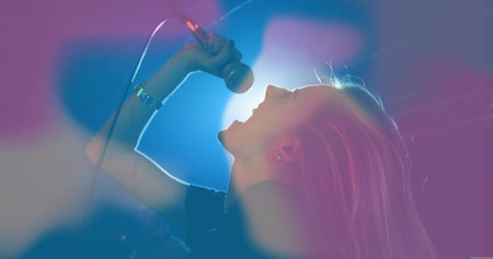 Performing solo female singer tilting head back gripping microphone on stage, with haze lighting....