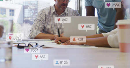 Collaborating professionals reviewing documents around laptop in boardroom, with smartphone icons....