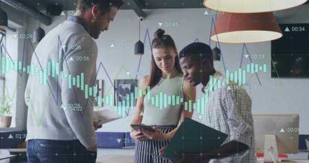 Collaborating co-workers in casual attire reviewing charts in office, with tablet, clipboard. Team, productivity, innovation, modernity, communication, analysis, corporateの写真素材