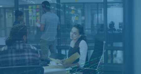 Interacting woman holding yellow folder by glass partition in office, with laptop and sticky notes. Collaboration, teamwork, brainstorming, idea generation, modern workplace, creative process, productivityの写真素材