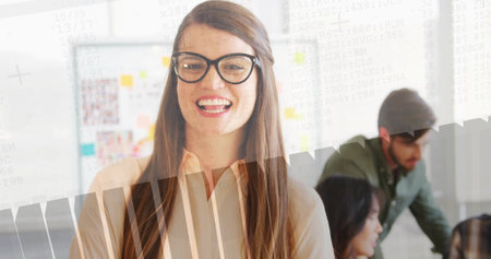 Smiling woman wearing blouse and glasses in office, with desk, sticky-note whiteboard, code overlay....