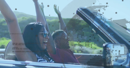 Driving convertible laughing duo wearing sunglasses throwing arms on country road, with seat belts. Adventure, freedom, leisure, landscape, lifestyle, outdoors, vibrantの写真素材