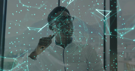 Man wearing glasses holding pen analyzing panel at office desk, with network and dotted globe....