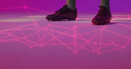 Standing male wearing black soccer cleats and athletic socks in studio, with glowing pink network....