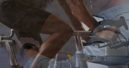 Pedaling male participant on exercise bike in fitness studio with trainer adjusting resistance knob....
