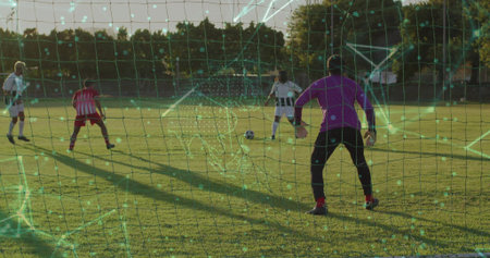 Dribbling player in white jersey guiding soccer ball near goal net on suburban field. Athletic, teamwork, competitive, sports, outdoor, active, dynamicの写真素材