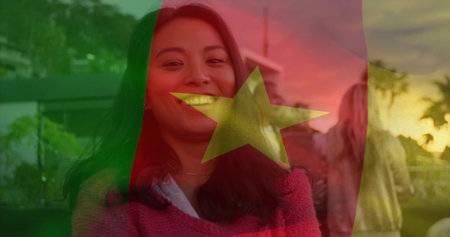 Smiling woman wearing red sweater standing on patio at sunset, with string lights and potted plants. Outdoor gathering, social event, casual celebration, evening ambiance, warm lighting, friendship, leisureの写真素材