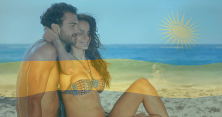 Embracing couple wearing swim trunks and bikini top sitting on calm beach, with flag overlay. Romance, vacation, seaside, leisure, harmony, serenity, vibrantの写真素材