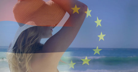 Lifting orange sun hat overhead, woman wearing swimsuit straps at beach, copy space. Seascape, leisure, tranquility, relaxation, outdoor, minimalist, wellnessの写真素材