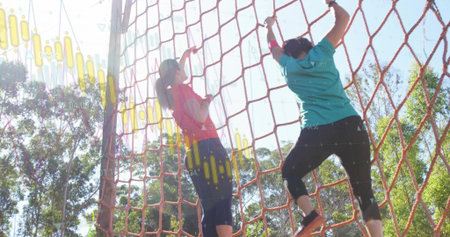 Two women climbing red cargo net in park obstacle course in sportswear, with data overlays. Adventure, teamwork, fitness, outdoor, dynamic, vitality, athleticismの写真素材