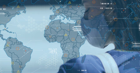 Analyst wearing face mask standing in control room, with world map and hex grid, copy space. Global, data visualization, futuristic, technology, security, analytics, digitalの写真素材