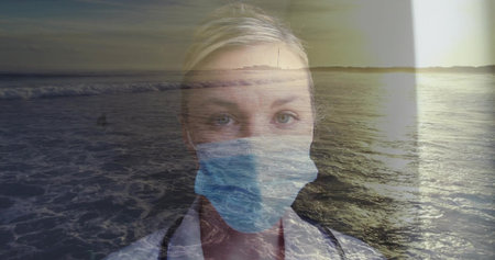 Blending doctor wearing face mask in double-exposure with coastal sunset waves, with stethoscope. Healthcare, wellness, serenity, medical, professional, outdoor, natureの写真素材