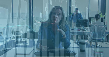 Tapping digital tablet, office woman working in open-plan office, with keyboard, coffee cup. Collaboration, teamwork, productivity, modernity, workplace, technology, businessの写真素材