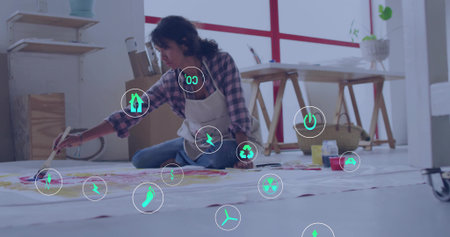 Painting artist wearing plaid shirt kneeling on paper in home studio with brush and paint jars. Creative, artistic, colorful, studio, contemporary, expressive, craftsの写真素材