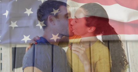 Kissing couple on wooden slats showing engagement ring and painted nails under American flag overlay. Romance, intimacy, patriotism, affection, love, devotion, commitmentの写真素材
