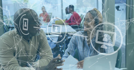 Coworkers reviewing documents and pointing at laptop in coworking space, with network overlay. Collaboration, professional, teamwork, connectivity, modern, innovation, digitalの写真素材