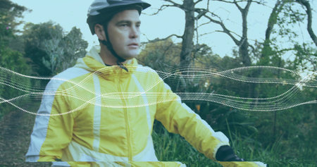 Riding light-skinned cyclist pedaling forest trail, with helmet, windbreaker, handlebars and gloves. Adventure, fitness, outdoor activity, rugged, nature, journey, explorationの写真素材