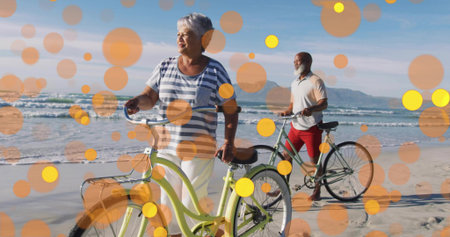 Pushing senior woman guiding pale green cruiser bicycle along sandy shoreline, with artistic filter. Outdoor, recreation, leisure, vacation, nature, serenity, minimalistの写真素材