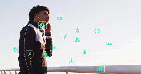 Pausing male runner wearing black jacket on pier railing, with floating eco icons, copy space. Activist, sustainability, urban, modern, health, innovation, eco-friendlyの写真素材
