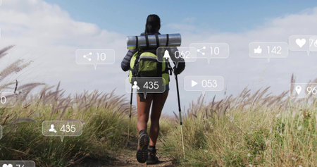 Walking female hiker carrying bright green backpack with trekking poles along rural trail, AR icons. Adventure, exploration, wilderness, outdoors, nature, technology, digitalの写真素材