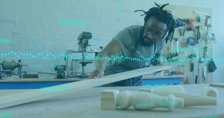 Inspecting apron-clad carpenter measuring plank at bench with drill press, pegboard, copy space....
