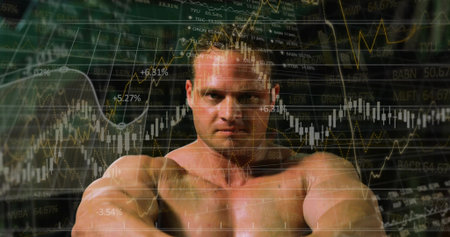 Showing shirtless athlete flexing muscles in studio, with stock market graphs and tickers. Fitness,...
