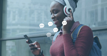 Standing woman adjusting over-ear headphones at transit stop, with phone and backpack, copy space....