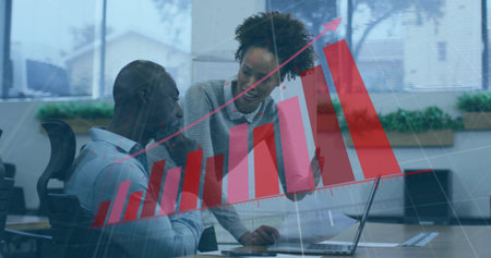 Collaborating at desk, two professionals analyzing documents on laptop, bar chart overlay in office. Teamwork, data visualization, business strategy, corporate, productivity, modern design, workplaceの写真素材