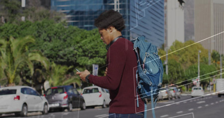 Man wearing burgundy sweater walking along urban street with smartphone, blue backpack, palm trees. Urban, pedestrian, fashion, modern, lifestyle, cityscape, casualの写真素材
