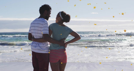 Embracing couple gazing at ocean waves on sandy shoreline, wearing striped shirt, patterned shorts....