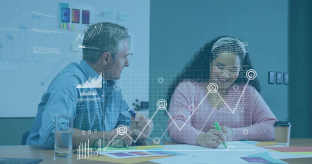 Man in blue shirt and woman in pink sweater reviewing data overlay in office meeting room. Collaboration, teamwork, data analysis, business meeting, modern office, creative process, professional environmentの写真素材