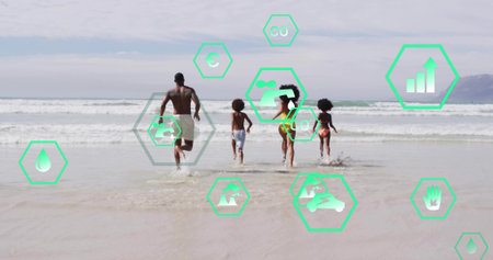 Running family of four splashing into surf at sandy beach, with green hexagonal icons. Family, adventure, leisure, outdoor, harmony, ocean, activityの写真素材